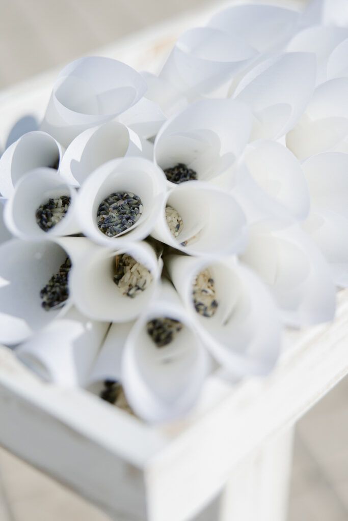 White paper cones filled with rice and lavender arranged in a wooden box.