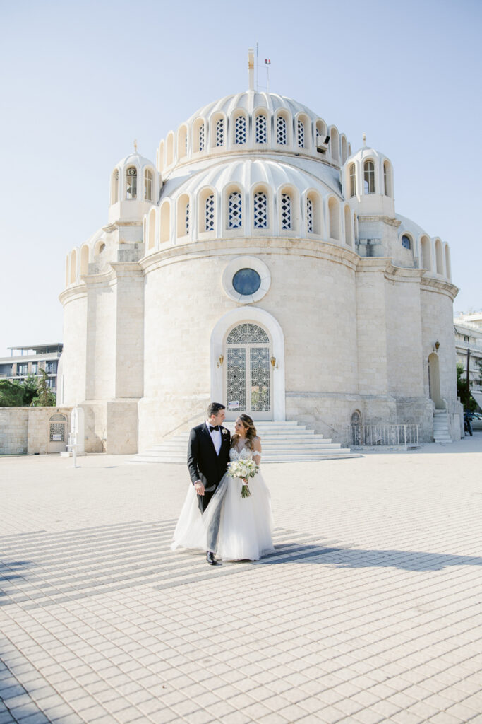 Bride and groom standing outside a large round stone building with arched windows and a domed roof