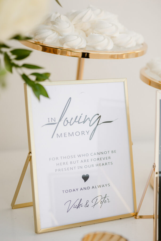 Framed memorial sign with gold border alongside white meringue cookies on a gold tray.
